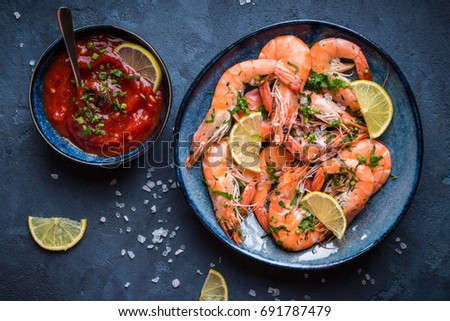 Cooked shrimps on plate with lemon, salt, sauce. Seafood appetizer. Top view. Big red prawns for lunch on rustic stone background. Healthy clean eating/diet. Shrimps close-up. Prepared large prawns