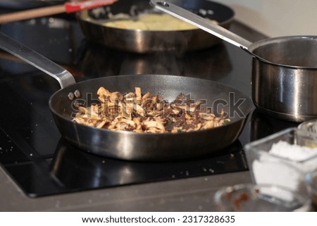 Cooked sliced mushrooms in a pan on electronic stove in kitchen.
