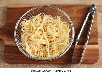 Cooked spaghetti in metal bowl on wooden cuttingboard