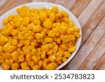 Cooked sweet corn kernels in bowl on wooden table