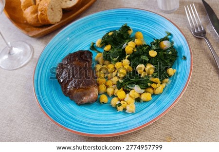 Cooked veal meat and vegetable side dish, top view. Boiled chickpeas with spinach perfectly complement baked veal..