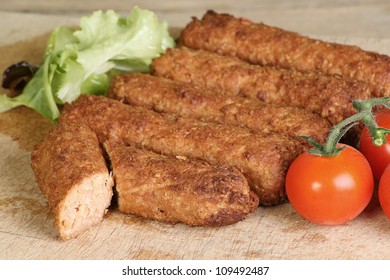 Cooked Vegetarian Sausage On A Wooden Board With Lettuce And Tomato