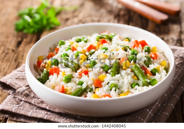 Cooked white rice mixed with\
colorful vegetables (onion, carrot, green peas, corn, green beans)\
in white bowl (Selective Focus, Focus in the middle of the\
dish)