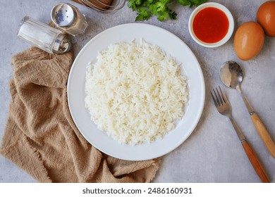 Cooked white rice or steamed rice in a white plate, with spoon and fork and eggs, thai jasmine rice, thai fragrant rice, top view food table	