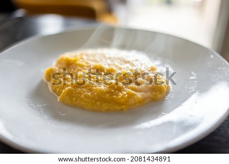 Cooked yellow southern american corn grits on plate as breakfast porridge with hot steam rising and texture of healthy cereal