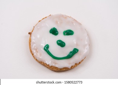 Cookie Decorated With Royal Icing Sugar, Green Smiley Face On White Icing. Happy Emotion On Cookie. Isolated, White Background. Selective Focus.