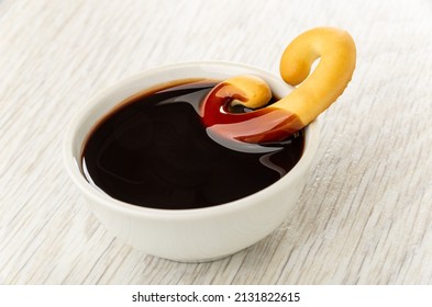 Cookie In Shape Pretzels Dipped In Chocolate Sauce In White Bowl On Wooden Table