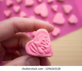 cookie with the word love engraved. Pink fondant, sugar paste. Pastry crafts. Valentine's Day. Mother's Day. Celebration. Hand holding a heart. Romantic relay. Detail.