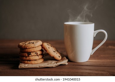 cookies with chocolate chips and a cup with a hot drink on a wooden table. - Powered by Shutterstock