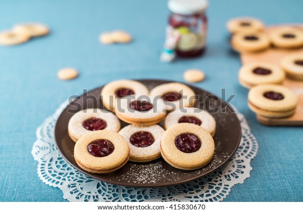 Cookies with jam, biscuits on a brown plate on\
a blue tablecloth