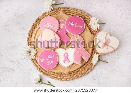 Cookies with pink ribbons and supportive words on white grunge background. Breast cancer awareness concept