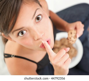 Cookies. Woman eating chocolate chip cookie.  Cute mixed race chinese / caucasian model.