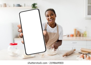 Cooking App. Cheerful Black Woman Baking In Kitchen And Showing Blank Smartphone At Camera, Excited African American Female Recommending Application With Online Recipes, Mockup, Collage - Powered by Shutterstock