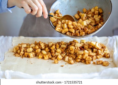
Cooking apple strudel. Girl is preparing a pie at home in an apron. Work with puff pastry. The process of making apple strudel. Rash fillings in puff pastry.apples are placed in the dough.Summer