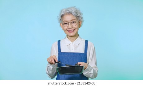 Cooking Asian Senior Woman With An Apron.