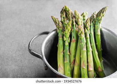 Cooking asparagus in a pot. Fresh asparagus boiled on water for cooking meal. Healthy food concept.