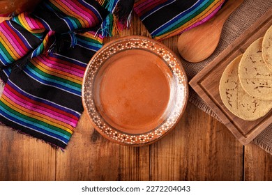 Cooking background with empty mud dish, mexican typical fabric on rustic wooden table. Table top view with copy space.