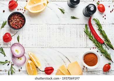 Cooking Background with spices: pepper, rosemary, paprika, lemon, onion, asparagus, olive oil,  tomato, parmesan cheese, cooking board and napkin on old wooden background. Culinary banner. Top view.
