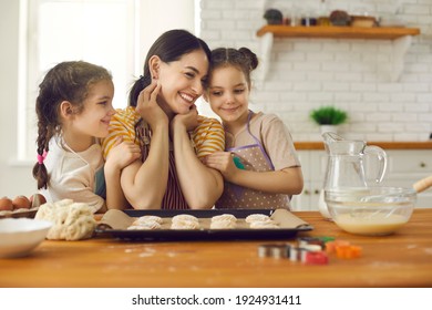 Cooking, Baking, Enjoying Time With Children Concept. Happy Smiling Woman Mother And Her Two Small Daughters Baking Sweet Bicsuits Together In Kitchen At Home