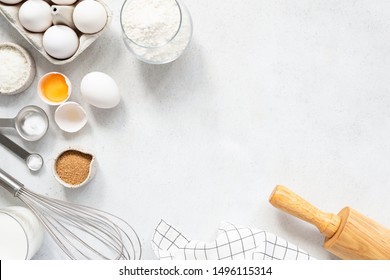 Cooking And Baking Ingredients Utensils On White Concrete Background. Kitchen Food Frame. Eggs Sugar Milk Whisker Rolling Pin And Measuring Spoons With Spices - Powered by Shutterstock