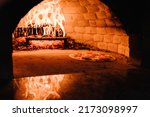 A cooking and baking pizza in a firewood oven. Pizza Margherita, four cheese or meat pizza into the oven. Italian traditional pizza is cooked in a stone wood-fired oven.