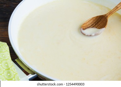 Cooking Of Bechamel Sauce In White Pan, Wooden Spoon