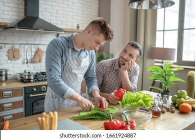 Cooking Breakfast. Gay Couple Of Young Men Cooking Breakfast In The Kitchen At Home, In A Good Mood.