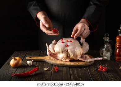 Cooking Broiler Chicken In The Kitchen By The Hands Of A Cook. Before Baking, The Cook Adds Red Viburnum To The Raw Chicken.