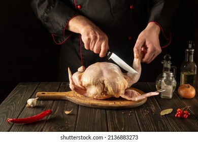 Cooking Broiler Chicken In The Restaurant Kitchen. The Chef Cuts Raw Chicken With A Knife. National Cuisine.