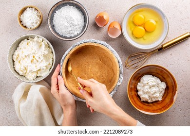 Cooking Cheesecake, Woman Hands Making A Cake Crust From Crushed Cookies And Butter. Main Ingredients: Soft, Fresh Cream Cheese, Eggs, Sugar Powder, Sour Cream, Corn Starch. Top View.