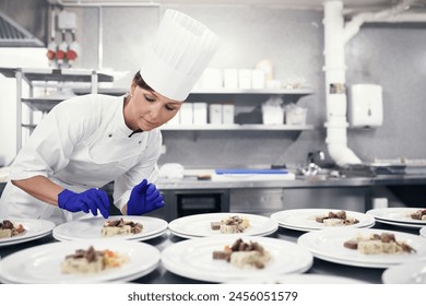 Cooking, chef and woman in kitchen with food in plate at restaurant for fine dining, service or hospitality industry. Expert, culinary professional and worker meal prep lunch or dinner for catering - Powered by Shutterstock