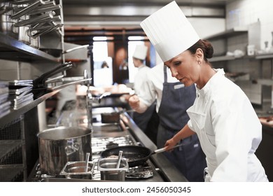 Cooking, chef and woman in kitchen at restaurant for fine dining, service or hospitality industry. Expert, culinary professional and worker with pan for meal prep, lunch or dinner for food catering - Powered by Shutterstock