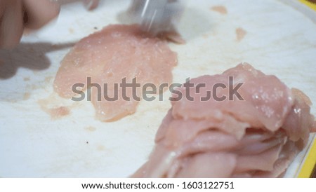 cooking chicken chops. Female hands cutting chicken breast on kitchen tables