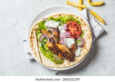 Cooking chicken gyros with vegetables, french fries and tzatziki sauce, top view. Greek food concept.