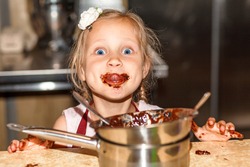 Cooking Chocolate. The Child Licks The Chocolate Around His Mouth. Little Girl  Kid With Chocolate On His Lips Prepares Hot Liquid Chocolate In A Pan