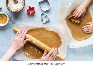 Cooking Christmas gingerbread. Mother and child prepare Xmas cookies. Raw dough and cutters for the holiday biscuits. Christmas family traditions. Light blue stone background. Top view.