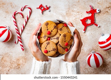 Cooking Christmas gingerbread. Woman's hands holding red nosed reindeer cookies box. Festive homemade decorated sweets for gift - Powered by Shutterstock