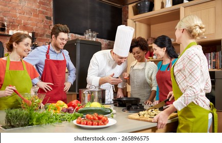 cooking class, culinary, food and people concept - happy group of friends and male chef cook cooking in kitchen - Powered by Shutterstock