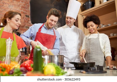 cooking class, culinary, food and people concept - happy group of friends and male chef cook cooking in kitchen - Powered by Shutterstock