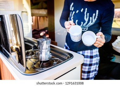 Cooking coffee in campervan, caravan or RV on camping trip. Woman is making coffee in the morning using italian kafetiera on a family vacation camping trip.