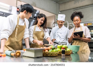 Cooking  course , senior Asian male chef in cook uniform teaches young asian and african american people cooking class students to prepare, mix ingredients for pastry foods, in restaurant stainless  - Shutterstock ID 2147004551
