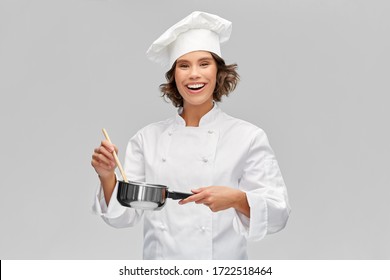 cooking, culinary and people concept - happy smiling female chef in toque with saucepan over grey background