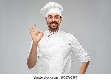 cooking, culinary and people concept - happy smiling male chef in toque showing ok hand sign over grey background
