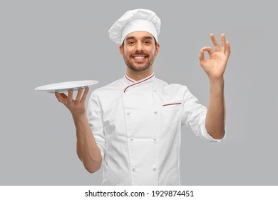 cooking, culinary and people concept - happy smiling male chef in toque holding empty plate over grey background - Powered by Shutterstock