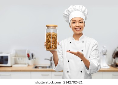cooking, culinary and people concept - happy smiling female chef holding jar with pasta over kitchen background