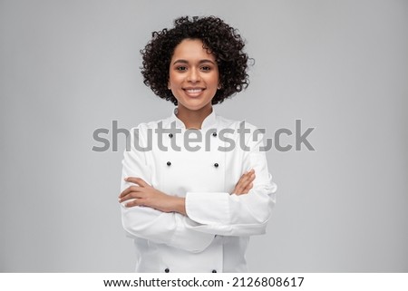 cooking, culinary and people concept - happy smiling female chef in white jacket over grey background