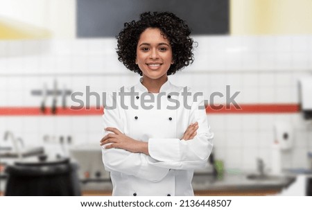 cooking, culinary and people concept - happy smiling female chef in white jacket over restaurant kitchen background