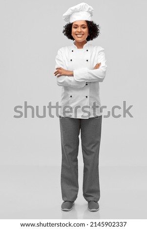 cooking, culinary and people concept - happy smiling female chef in white toque and jacket over grey background