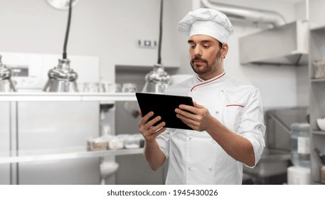 cooking, culinary and people concept - male chef in toque with tablet pc computer over restaurant kitchen background - Powered by Shutterstock