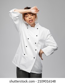 cooking, culinary and people concept - tired female chef in white jacket over grey background